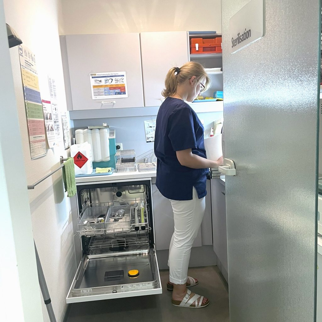 Eine zahnmedizinische Fachangestellte arbeitet im Sterilisationsraum.