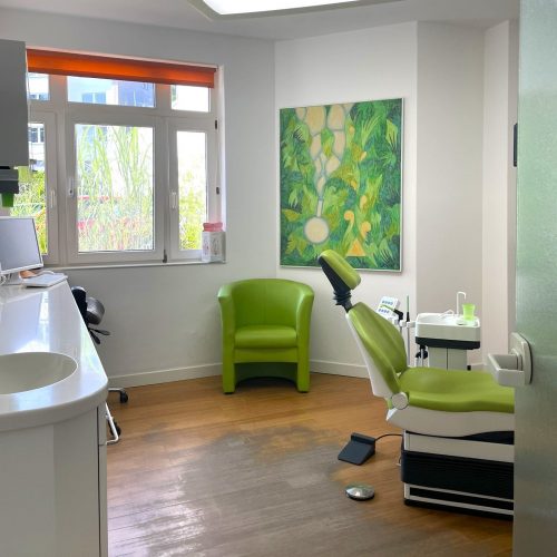 Ein Behandlungszimmer in der Zahnarztpraxis Werner Schippers mit einem grünen Behandlungsstuhl.