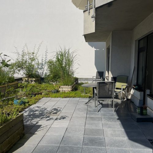 Eine Terrasse mit einem Garten im Hintergrund
